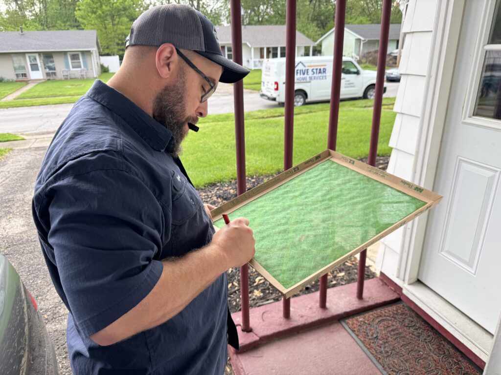 Air Conditioner Filters: Essential Maintenance & Replacement Tips 2 HVAC tech replacing an air conditioner filter.